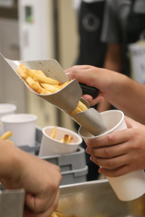 Culinary students pour fries into cups that they will sell for $3.